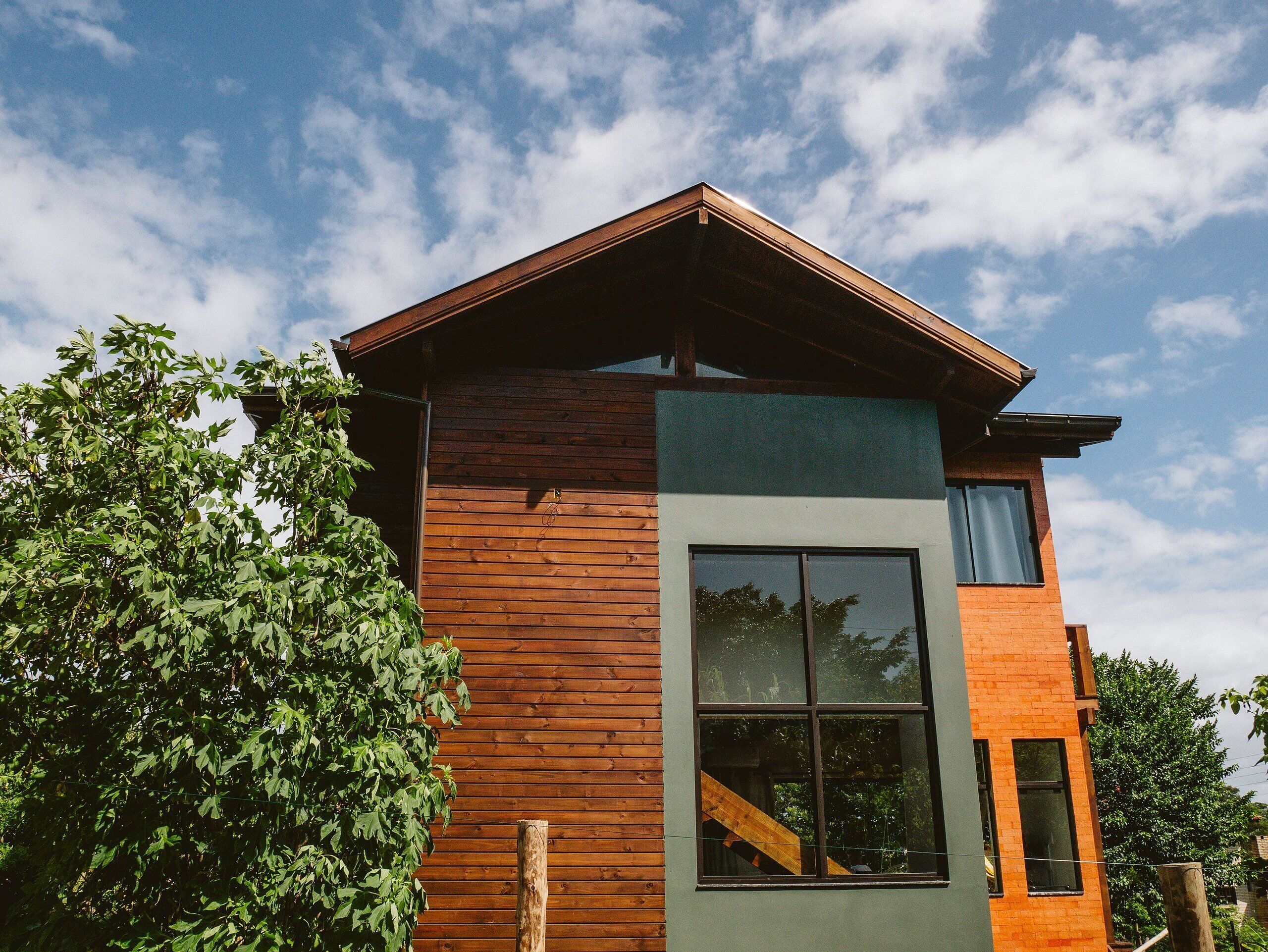 Un bâtiment moderne à deux étages, doté d’une façade en bois et d’une grande fenêtre.