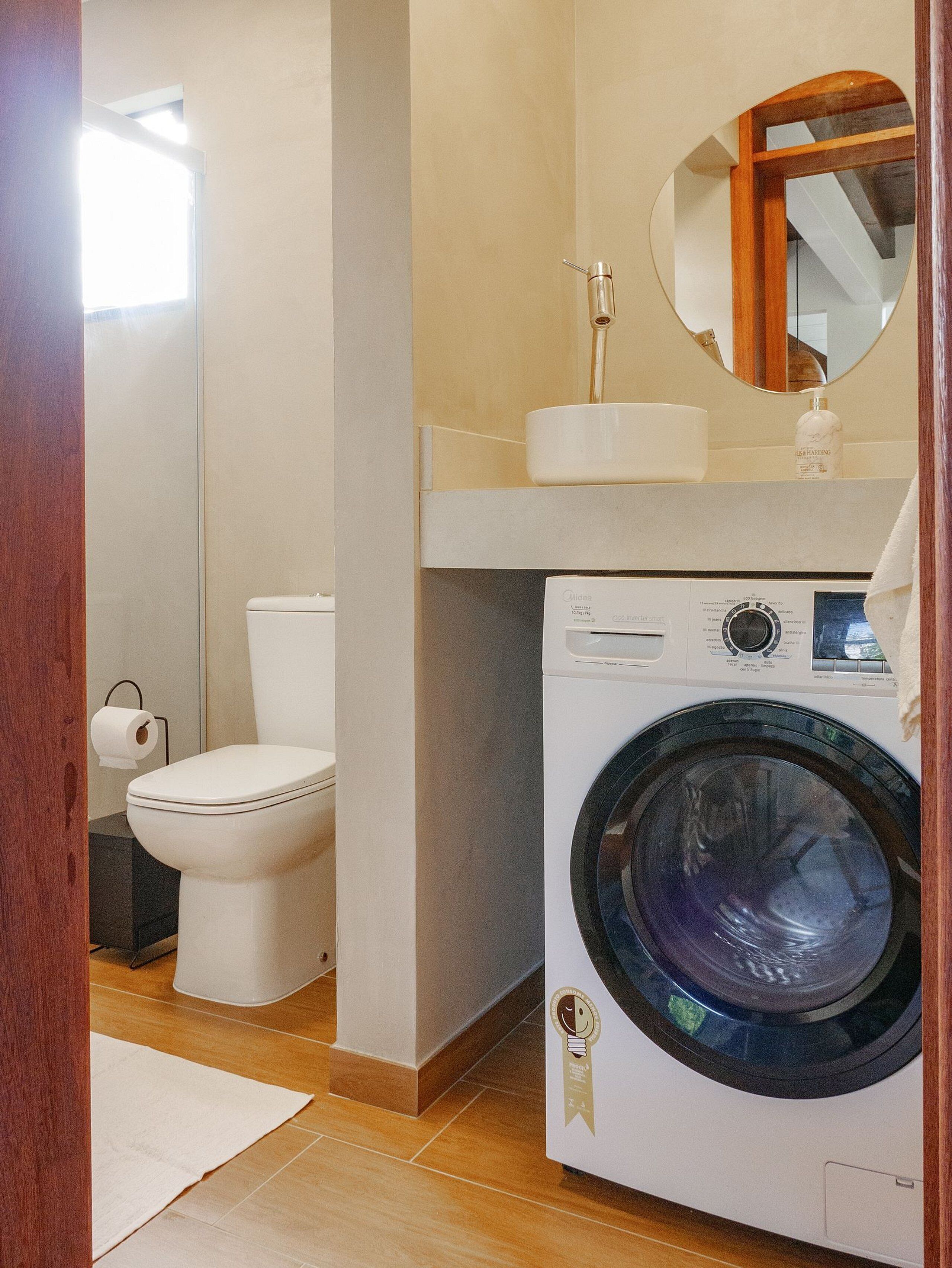 Un baño pequeño con inodoro, lavadora y espejo.
