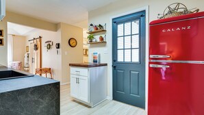 A kitchen with a black marble countertop, white cabinets, a red Galanz refrigerator, and a blue door. - Zanesville Apartment w/ Porch - 3 Mi to Downtown! (Zanesville)