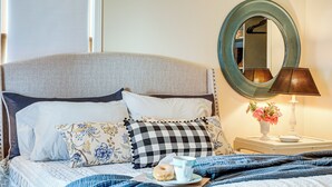 A neatly made bed with a checkered pillow, a cup of coffee, and a donut on a tray. - Zanesville Apartment w/ Porch - 3 Mi to Downtown! (Zanesville)