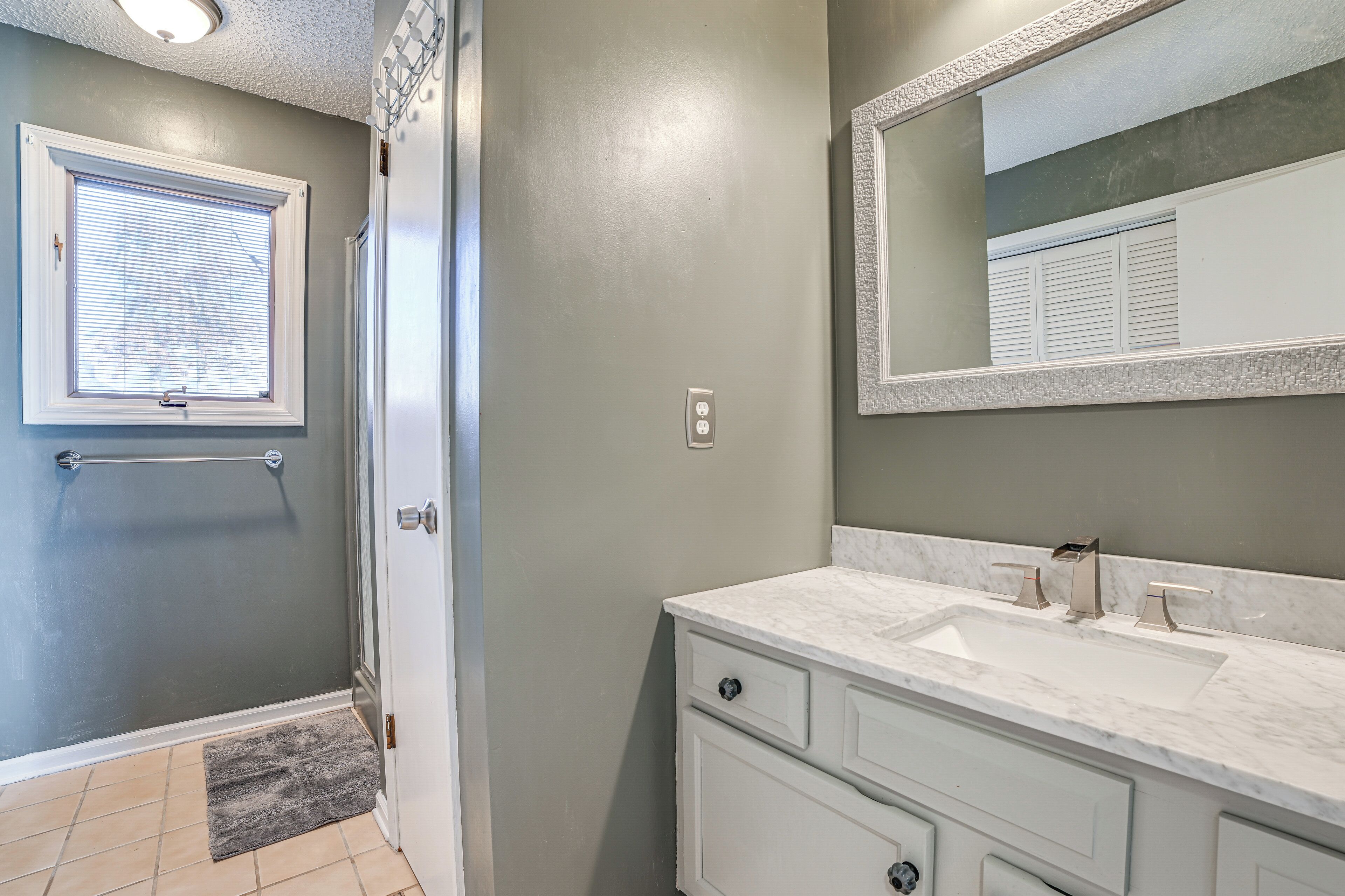 A bathroom with a white vanity, a large mirror, and a shower area with a glass door.