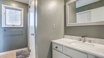 A bathroom with a white vanity, a large mirror, and a shower area with a glass door.