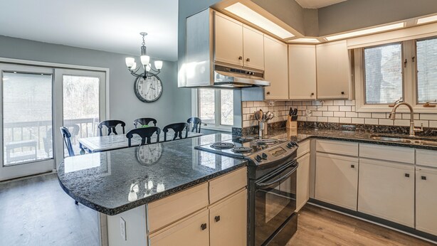 A kitchen with a central island, stainless steel appliances, and a dining area with chairs.