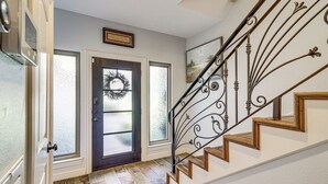 Un escalier orné de rampes en métal ouvragé et de marches en bois, menant à une porte décorée d’une guirlande.