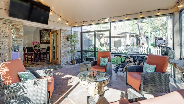 Une terrasse ensoleillée, meublée de meubles en osier, avec une table basse en verre et une vue sur le jardin.