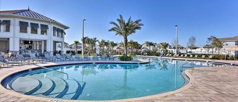 A swimming pool with a curved design, surrounded by lounge chairs and palm trees.