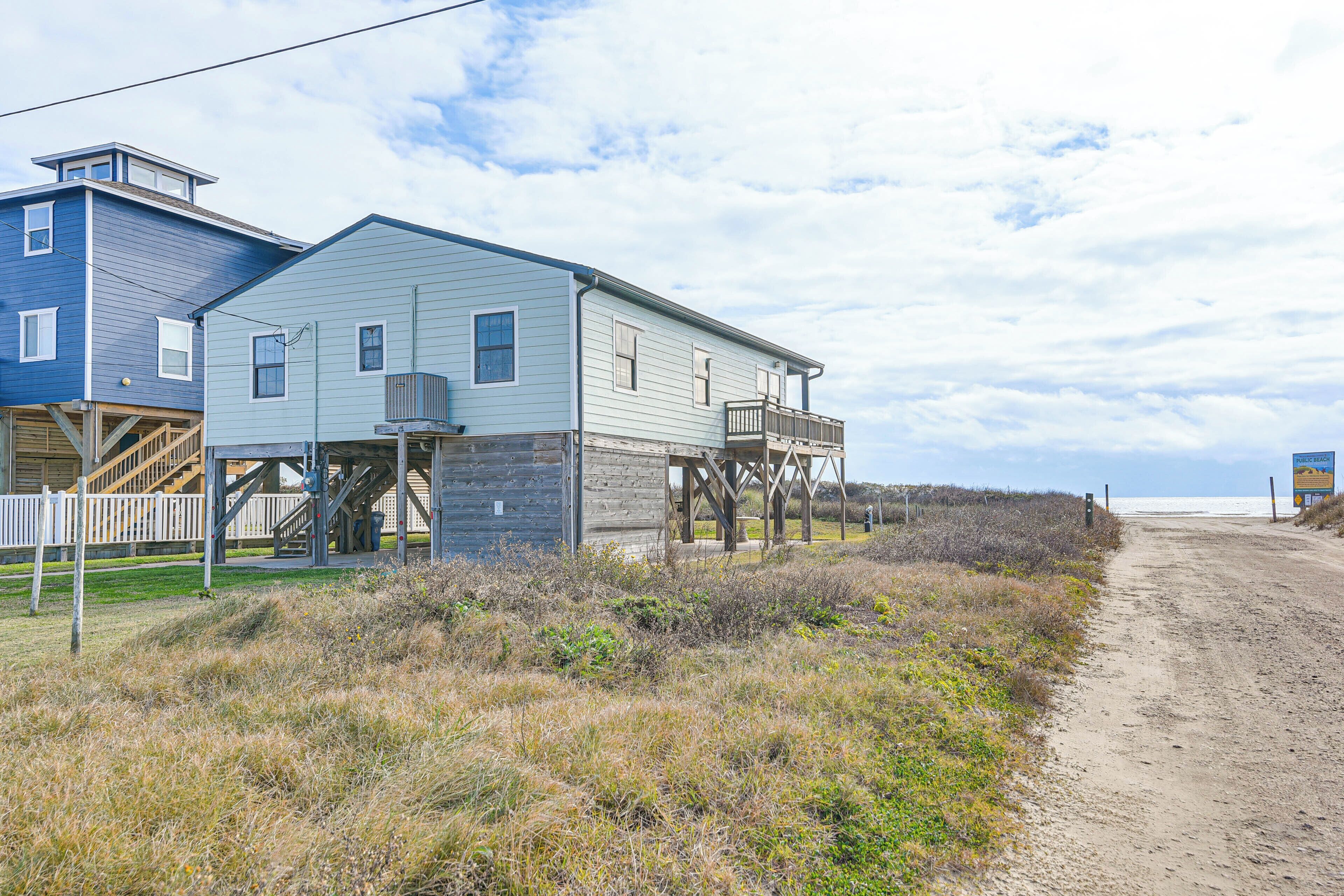 Un edificio frente al mar con una terraza de madera y vistas a la playa.