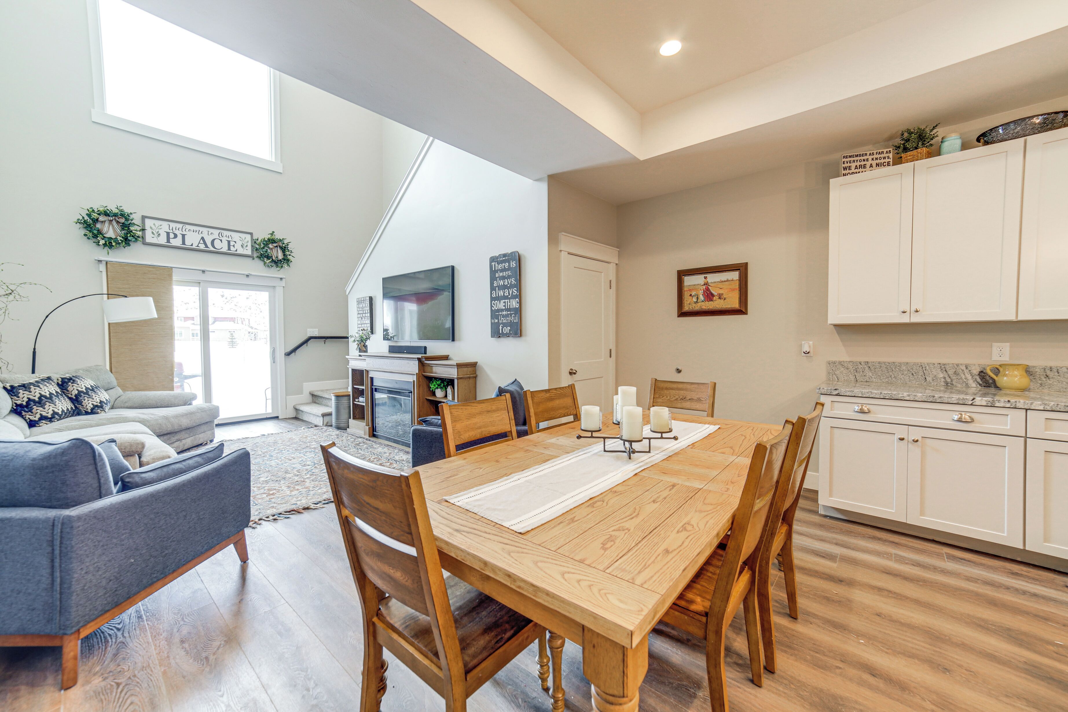 A spacious living room with a large wooden dining table, comfortable seating, and a view of the outdoors.