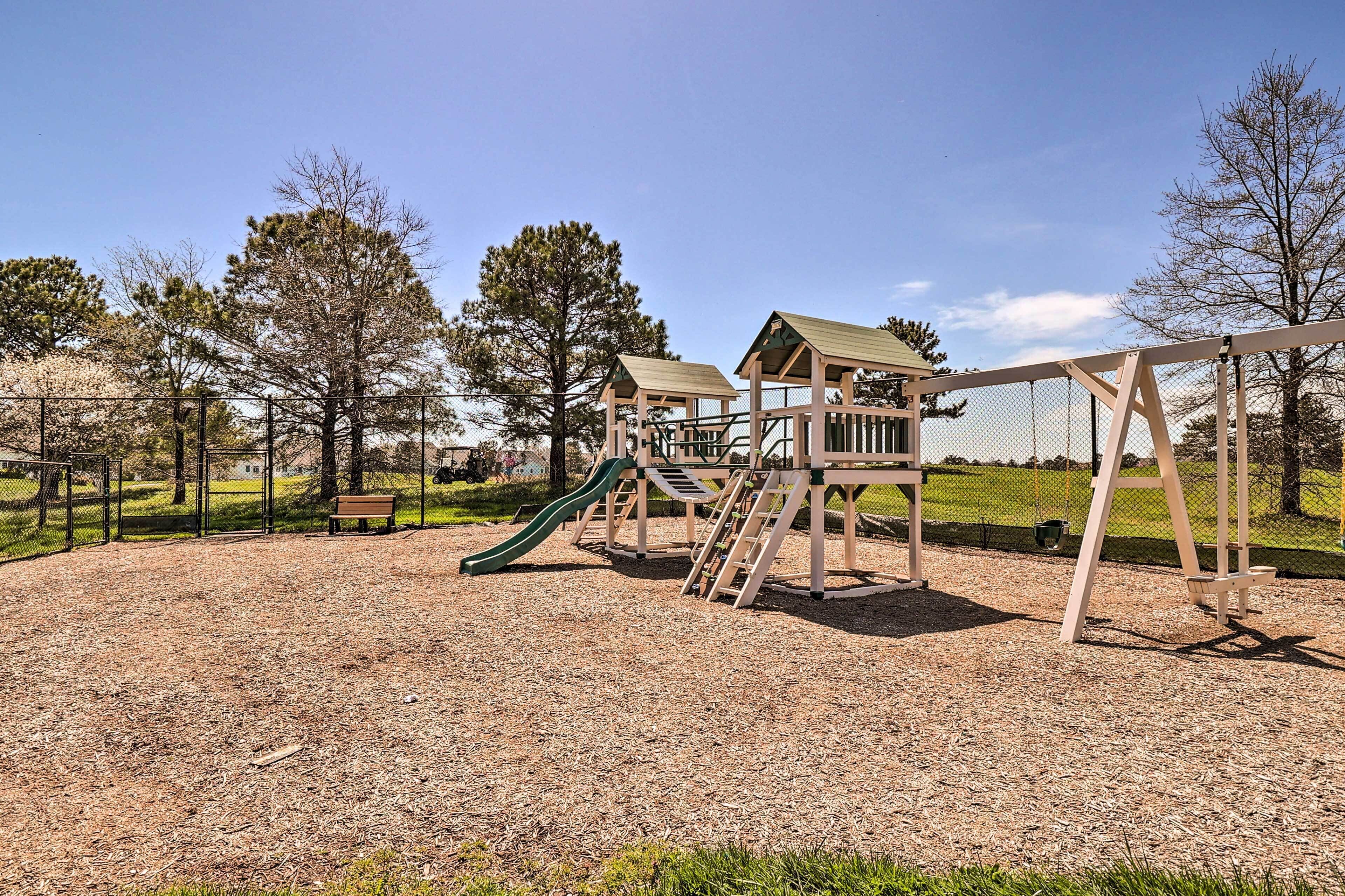 A playground with a slide, climbing structures, and a wooden playhouse.
