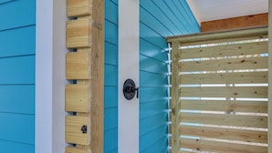 Una verja de madera con un cerrojo de metal, cerca de madera y pared azul y blanca con una puerta de madera.