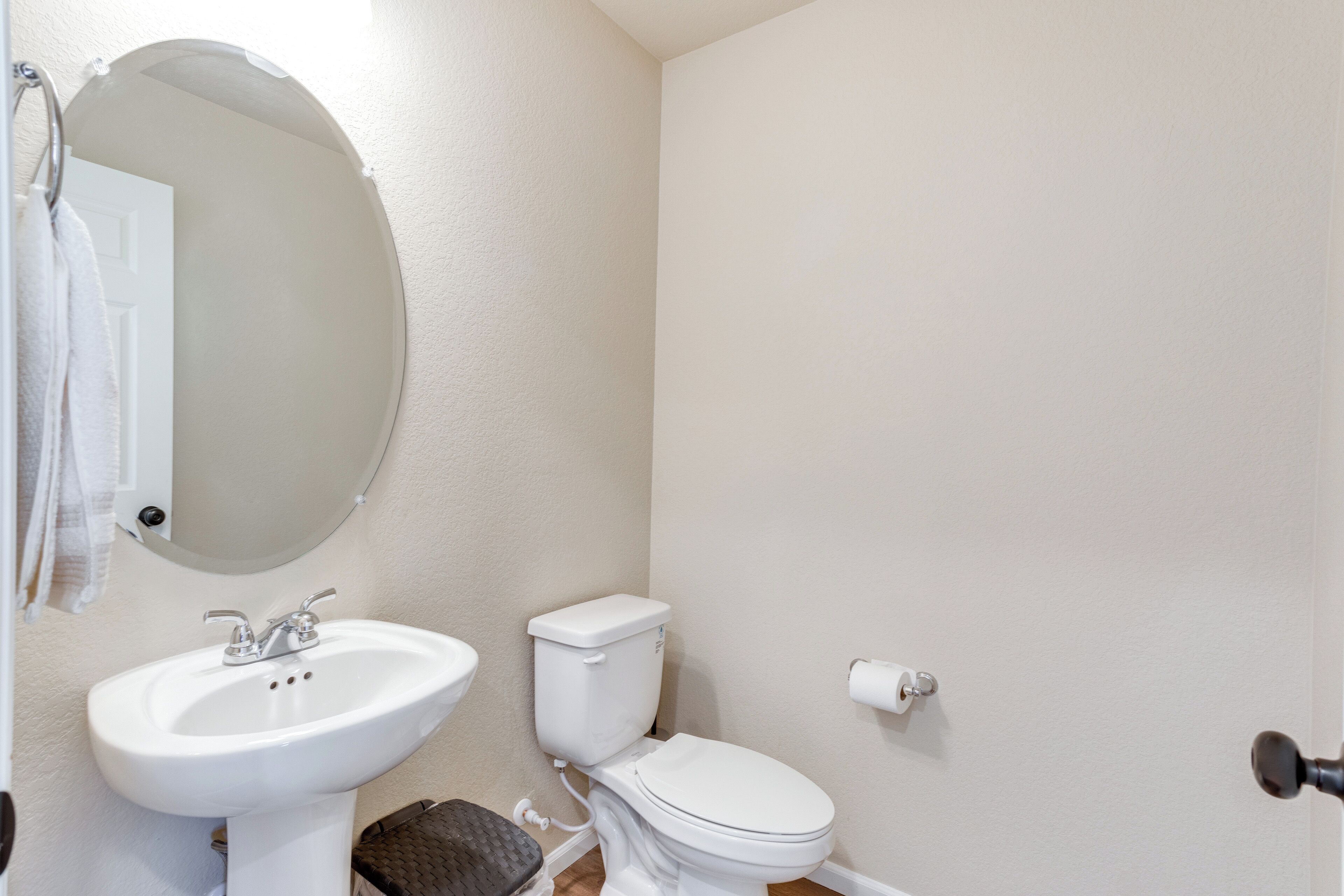 Une salle de bain avec un lavabo blanc, des toilettes et un miroir.