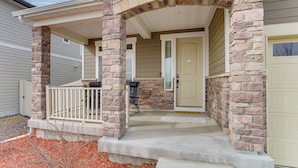 A house with a stone facade, a covered porch, and a garage door. - 17 Mi to Dtwn Denver: Modern Aurora Home w/ Yard (Aurora)