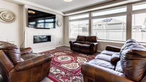 A living room with leather sofas, a large TV, and a patterned rug. - 17 Mi to Dtwn Denver: Modern Aurora Home w/ Yard (Aurora)