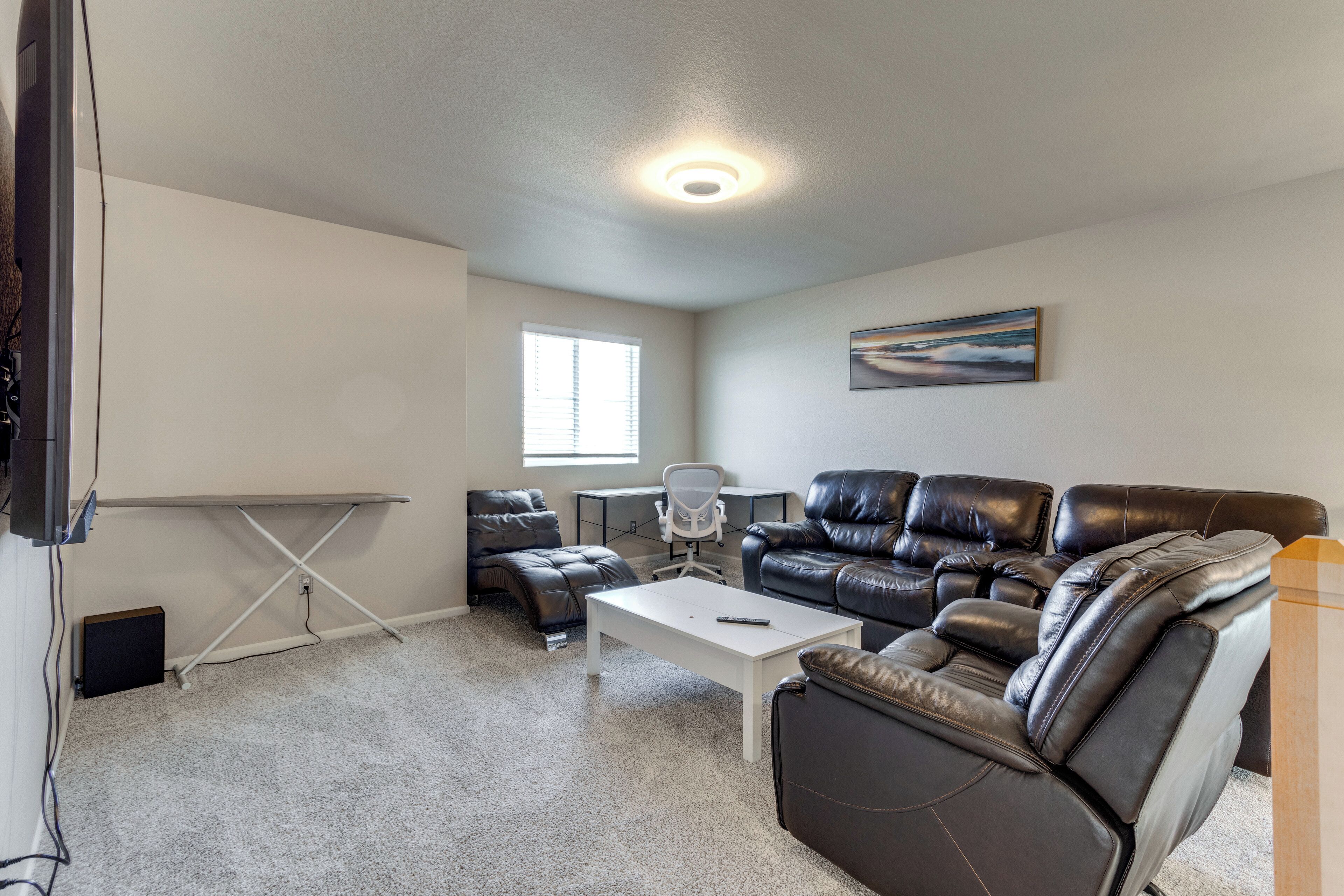 A living room with a sofa, a coffee table, a desk, and a chair.