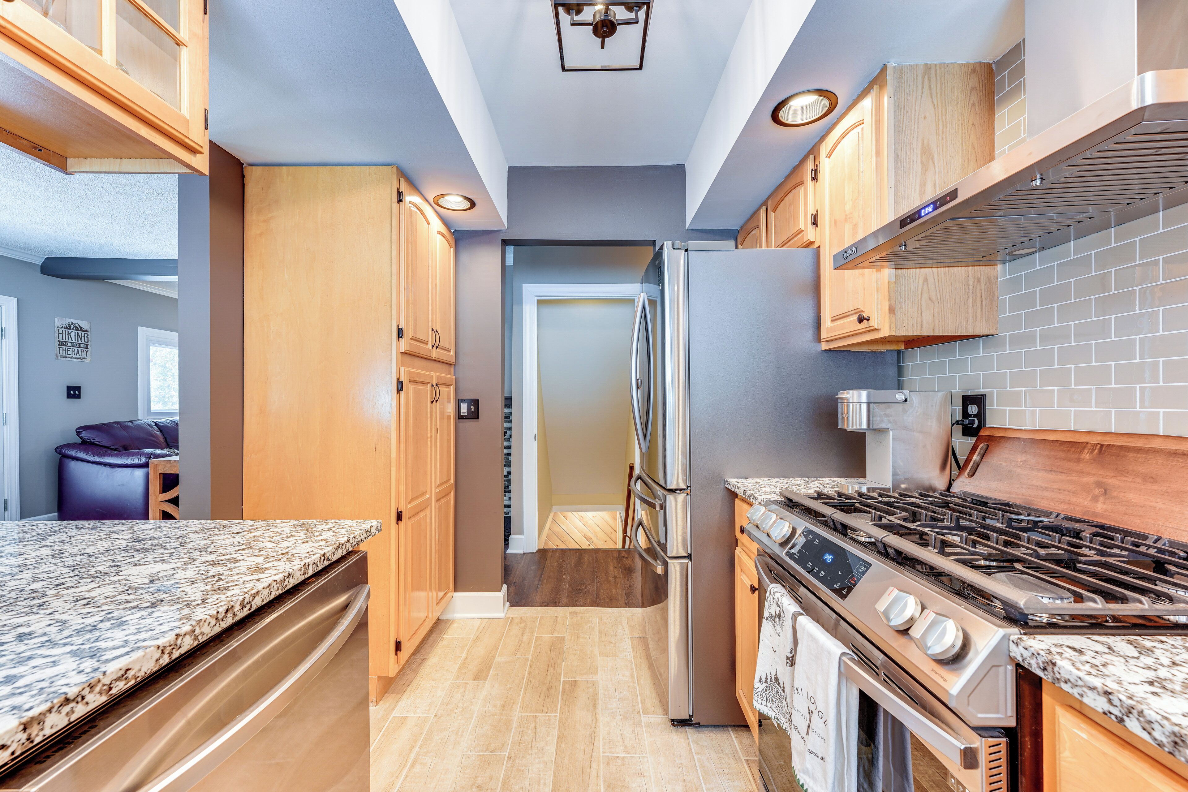 Una cocina moderna con encimeras de granito, electrodomésticos de acero inoxidable, armarios de madera y salpicadero de azulejos.