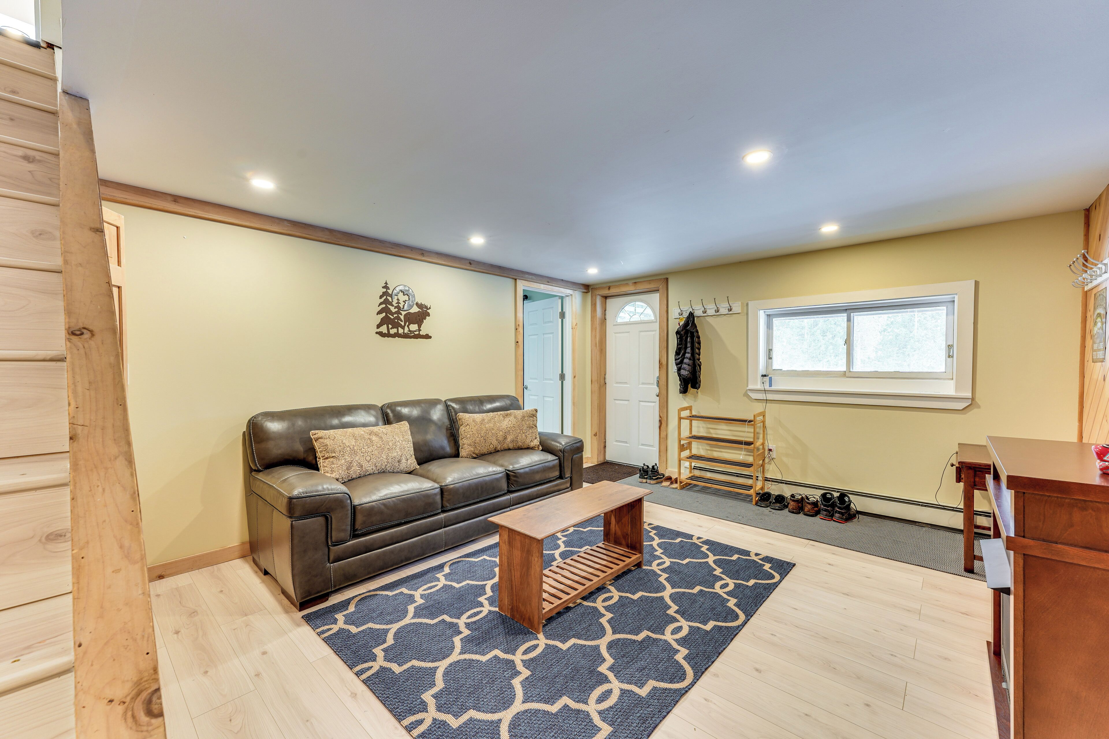 A living room with a brown leather sofa, a wooden coffee table, and a patterned rug.