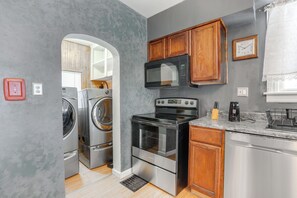 Una cocina compacta con electrodomésticos de acero inoxidable, armarios de madera y horno empotrado.