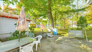 An outdoor patio with a table and chairs, a covered umbrella, and a playground in the background. - Niles Vacation Rental Near St Joseph River! (Niles)