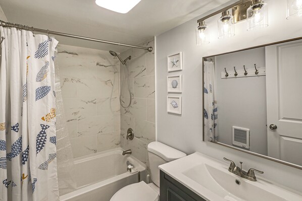 Un baño con ducha, inodoro, lavabo y un espejo grande.