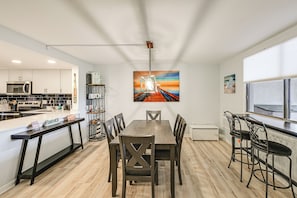 A modern kitchen with white cabinets, a wooden dining table, and bar stools.