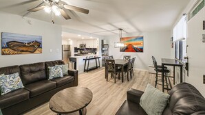 Una sala de estar moderna con sofá de cuero, mesa de comedor y ventilador de techo.