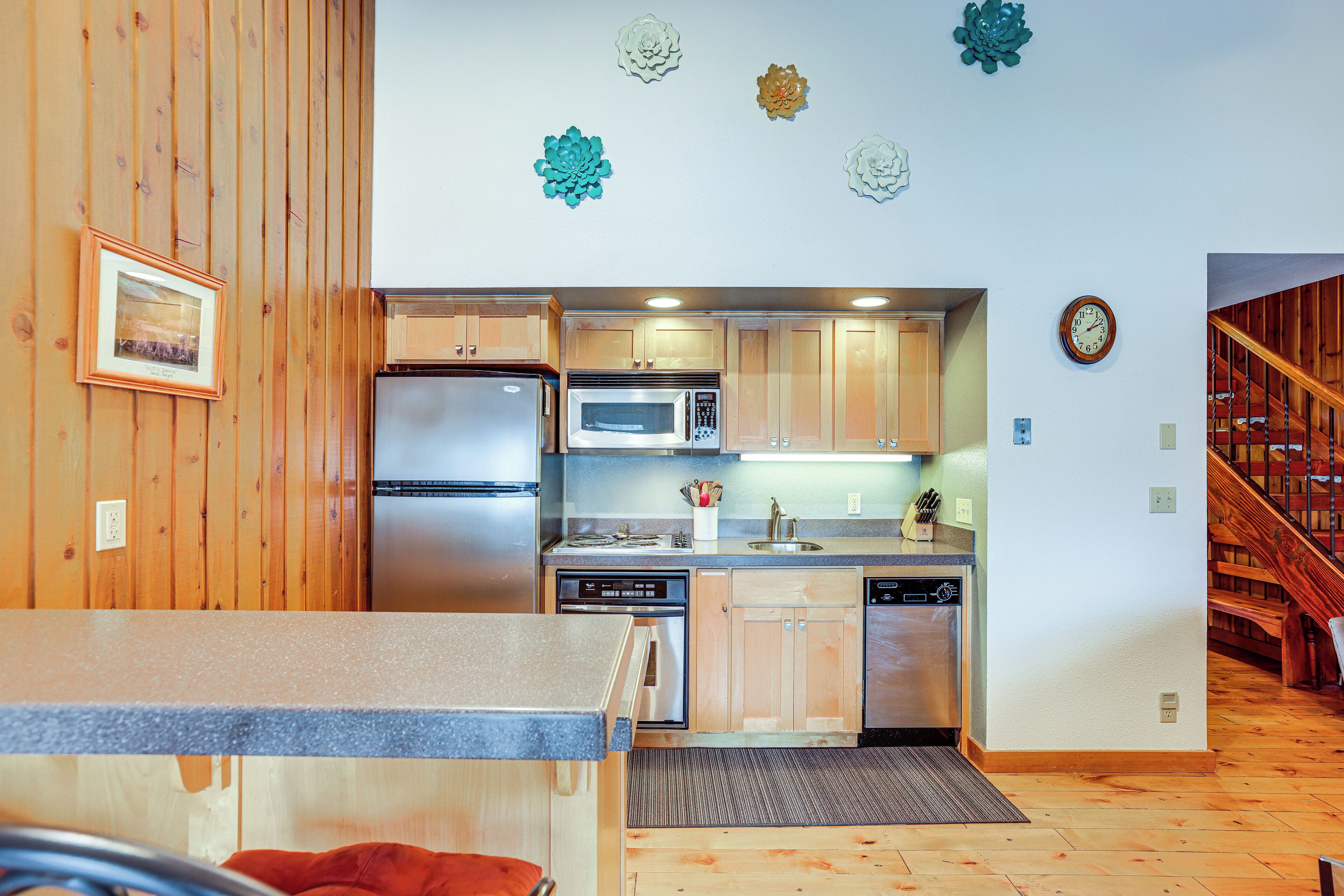 A modern kitchen with wooden cabinets, stainless steel appliances, and decorative wall art.