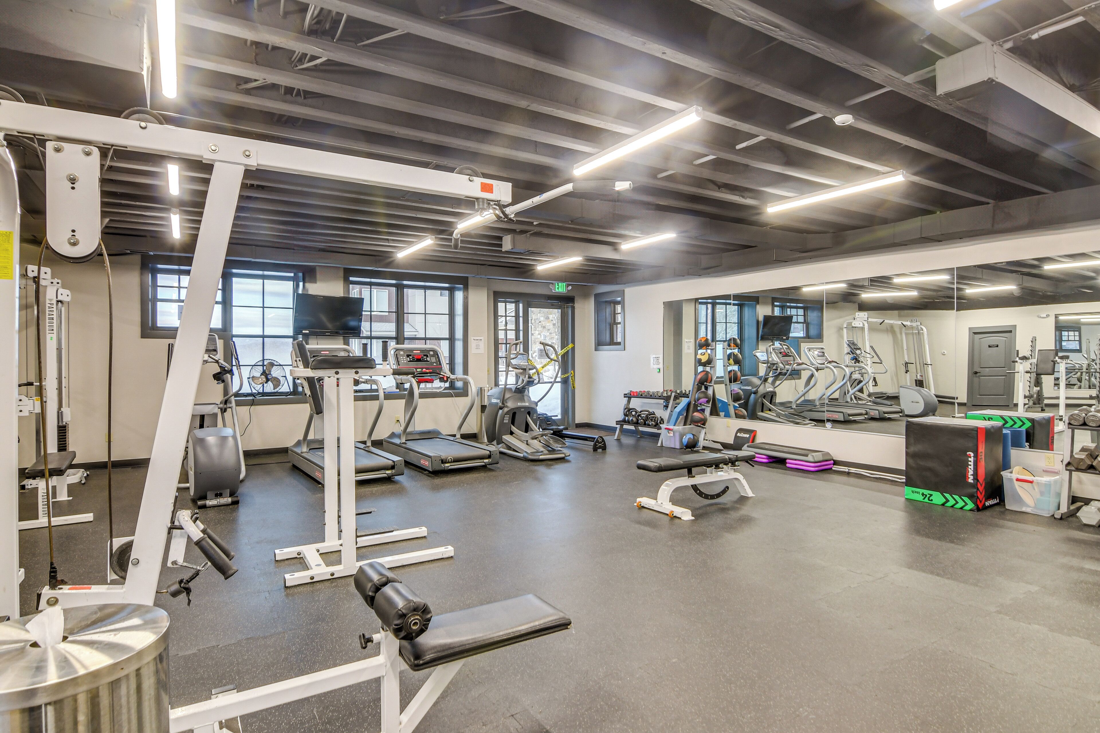 Ein Fitnessstudio mit Laufbändern, Crosstrainern und Gewichten.