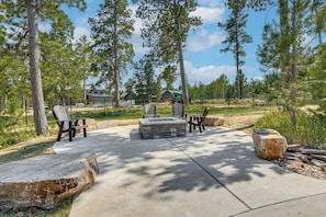 A patio area with a stone fire pit, seating, and a surrounding fence. - Modern Lead Cabin w/ Hot Tub, 6 Mi to Skiing! (Lead)