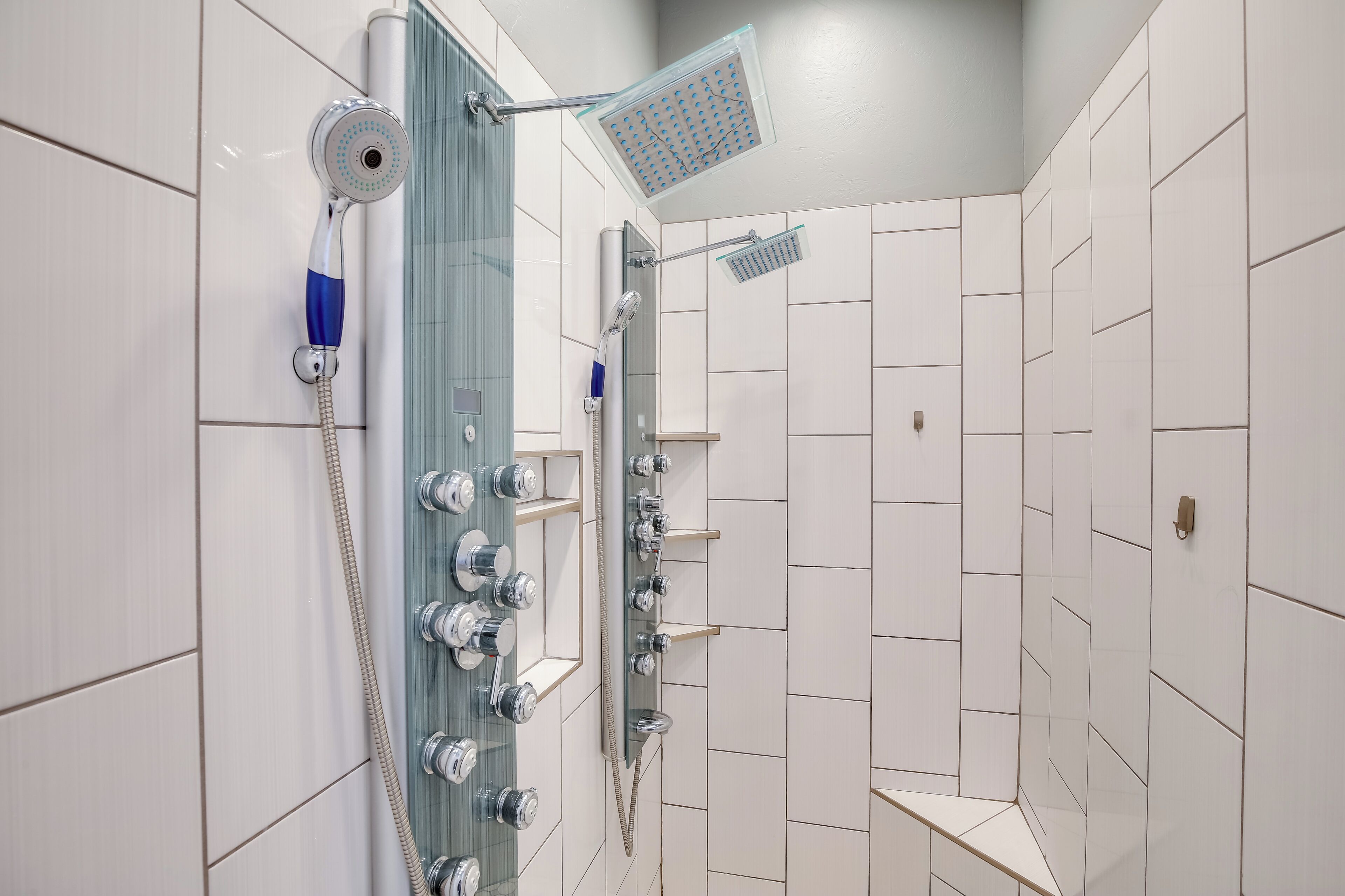 Une salle de bain moderne avec une douche à parois de verre, des robinetteries chromées et des murs recouverts de carreaux blancs.