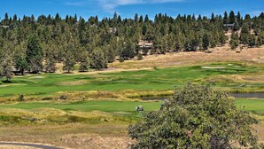 A golf course with a clubhouse, surrounded by dense forest and a clear sky. - Klamath Falls Townhome w/ Deck & Resort Amenities! (Klamath Falls)