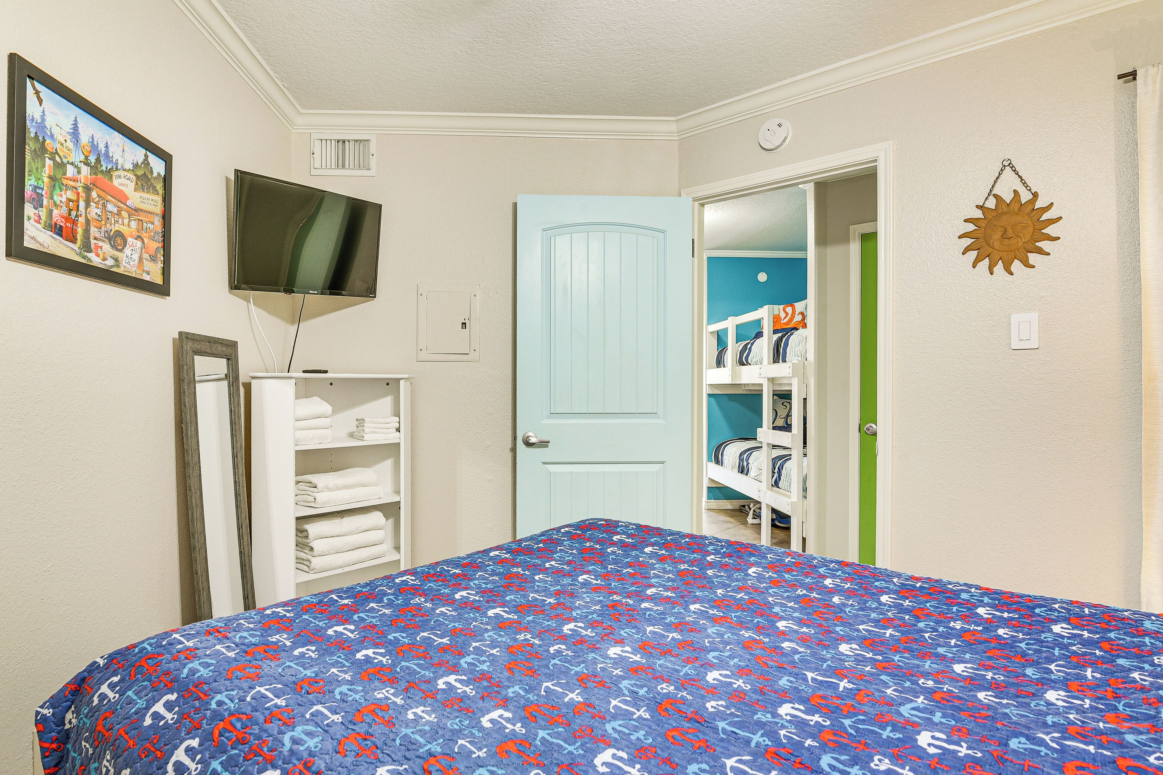 Une chambre à coucher comprenant un lit, une télévision, une armoire et une porte donnant sur une autre pièce.