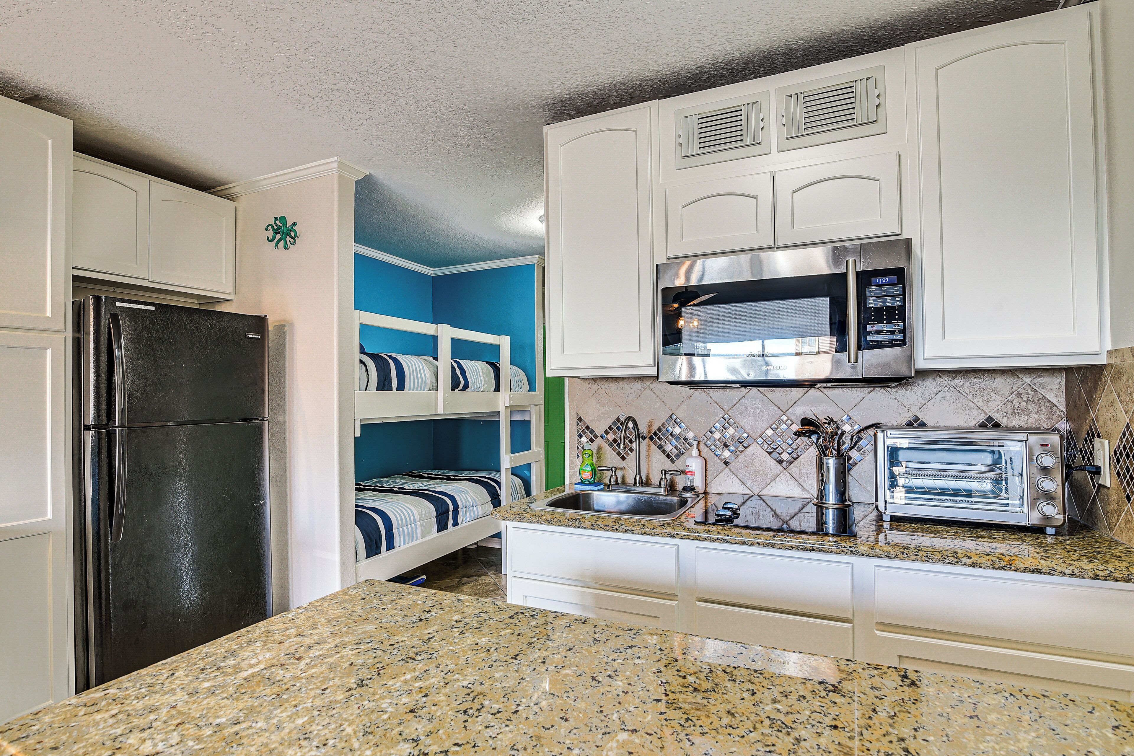 A kitchen with white cabinets, a stainless steel refrigerator, a microwave, and a toaster.