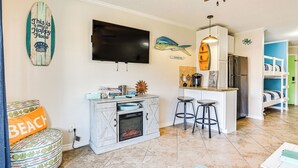 Una cocina con televisión, taburetes de bar y horno empotrado.