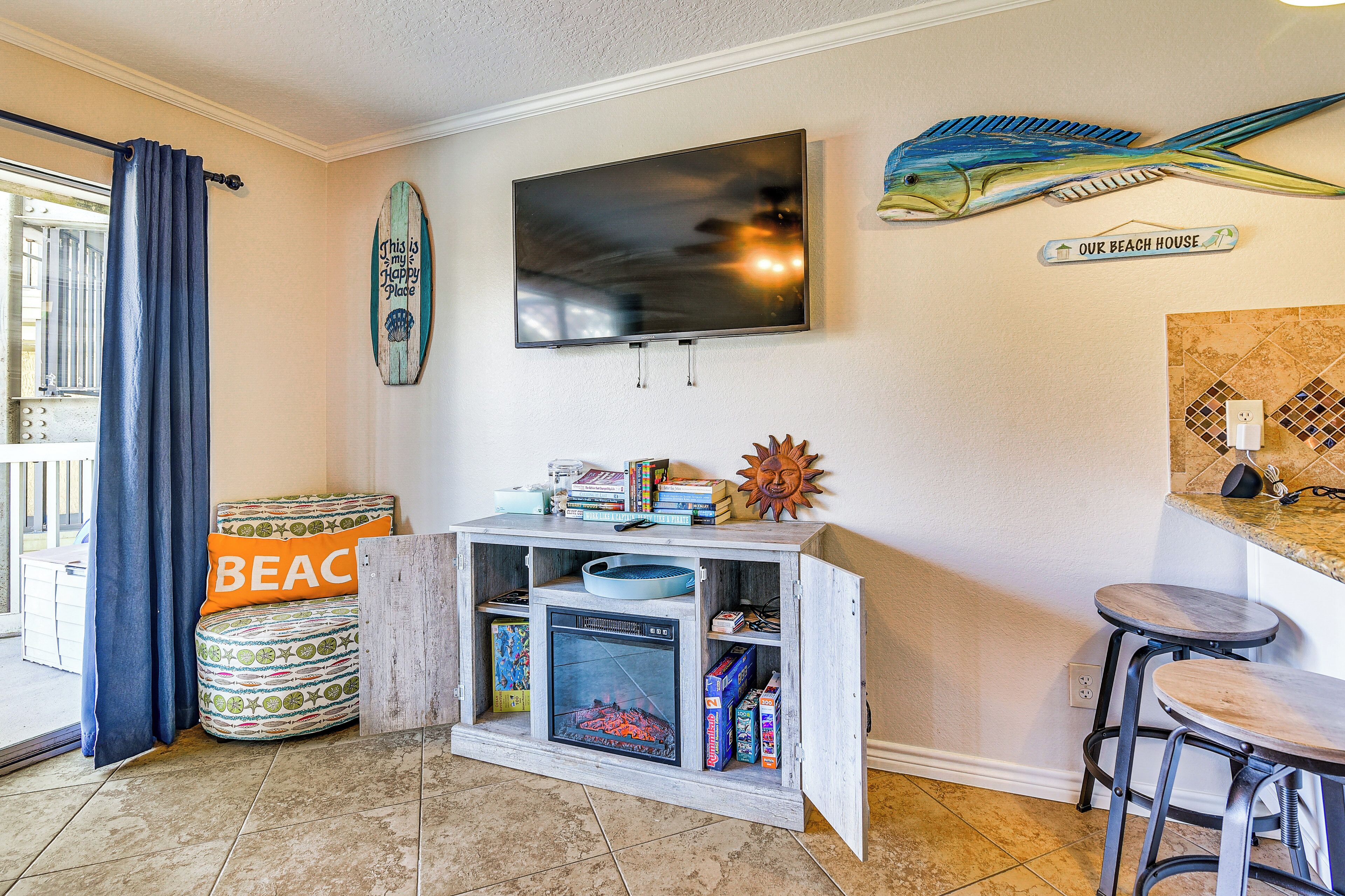A beach-themed living area with a TV, books, and a surfboard decoration.