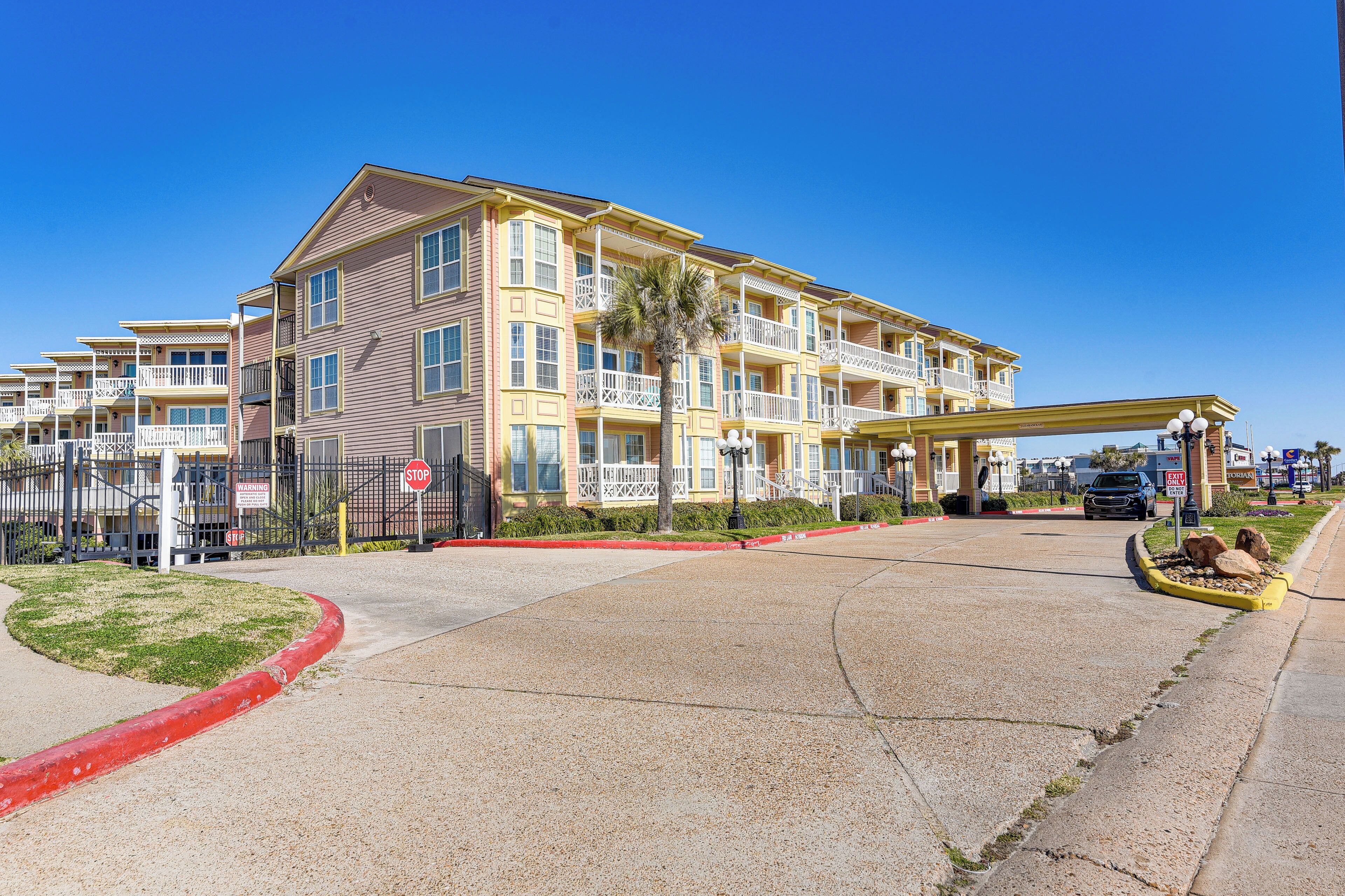 A multi-story hotel with a central courtyard, a covered walkway, and a parking area.