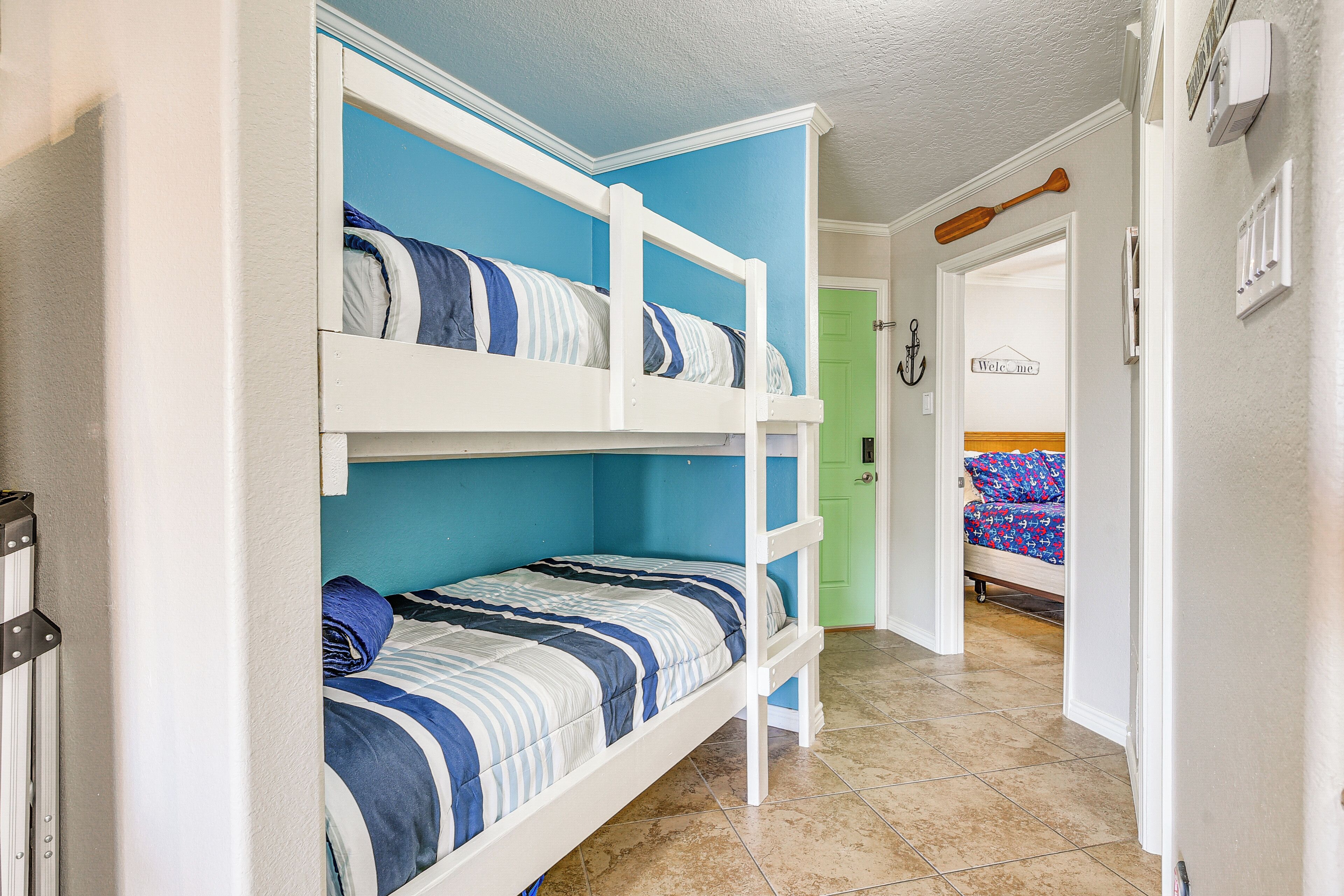 A bunk bed room with blue walls and a green door.