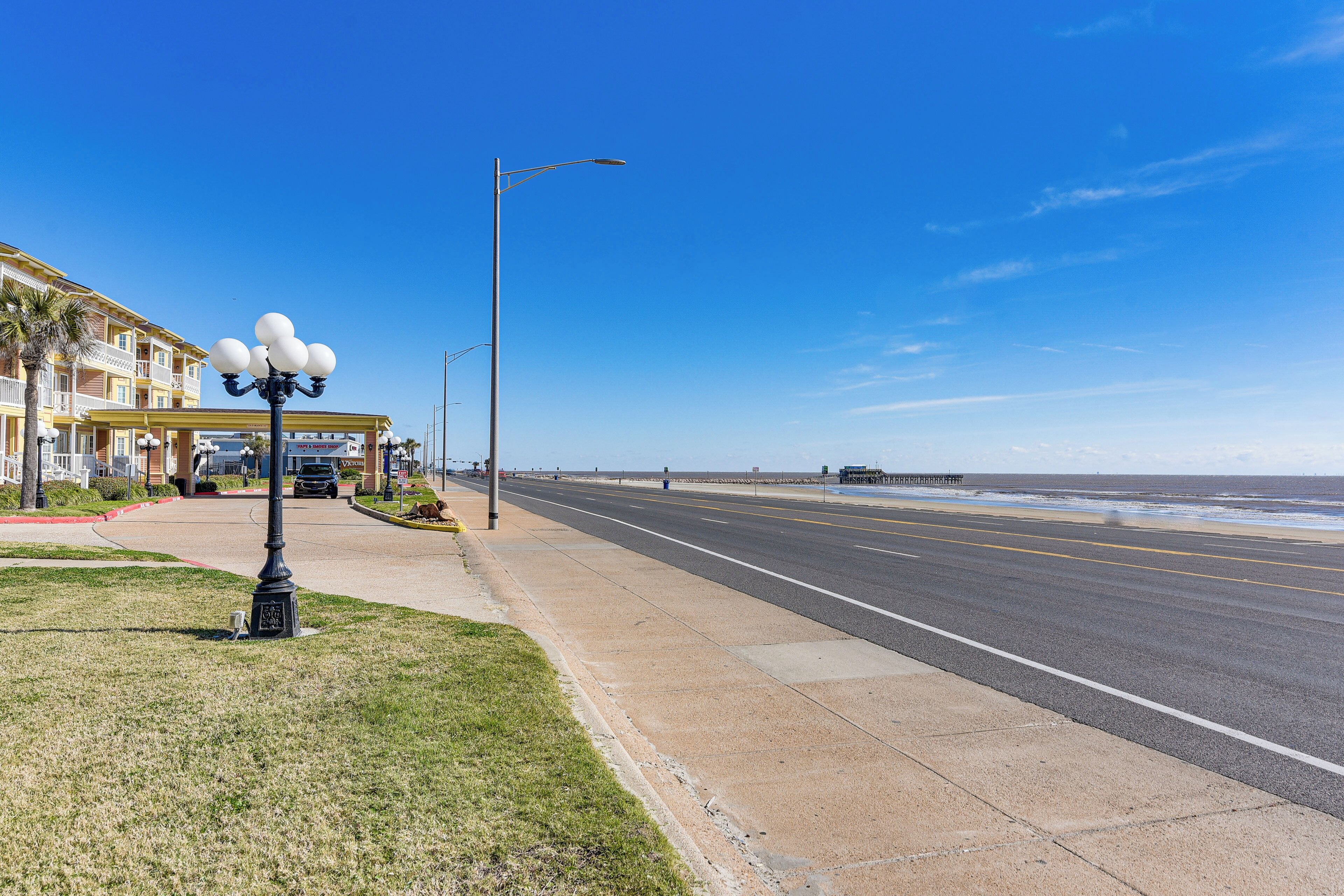 A coastal road with a sidewalk, a street lamp, and a building with balconies.