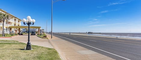 A coastal road with a sidewalk, a street lamp, and a building with balconies.