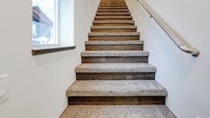 A staircase with stone steps and a wooden handrail, leading to a landing with a window. - Family-friendly Fairbanks Home: Chena River Access (Fairbanks)