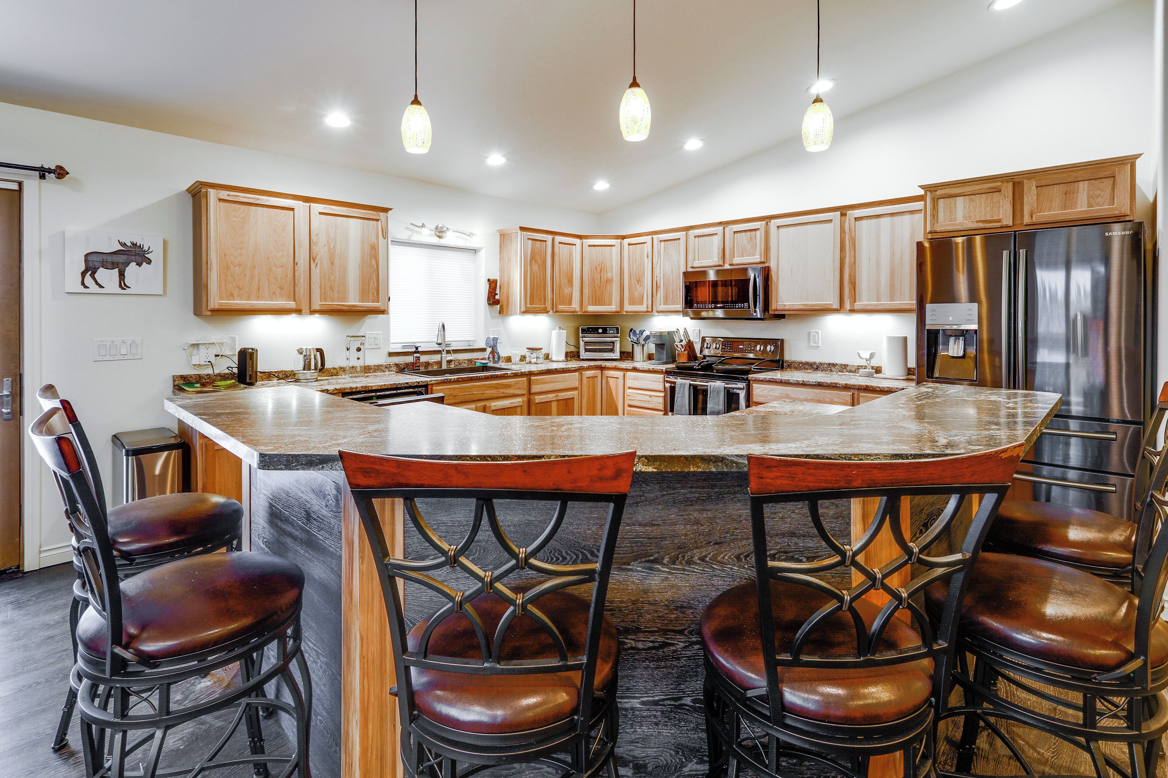 A modern kitchen with wooden cabinets, stainless steel appliances, and a central island with bar stools.