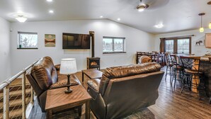 A spacious living area with leather sofas, a wooden coffee table, and a fireplace. There are multiple windows providing natural light and a view of the outdoors. - Family-friendly Fairbanks Home: Chena River Access (Fairbanks)