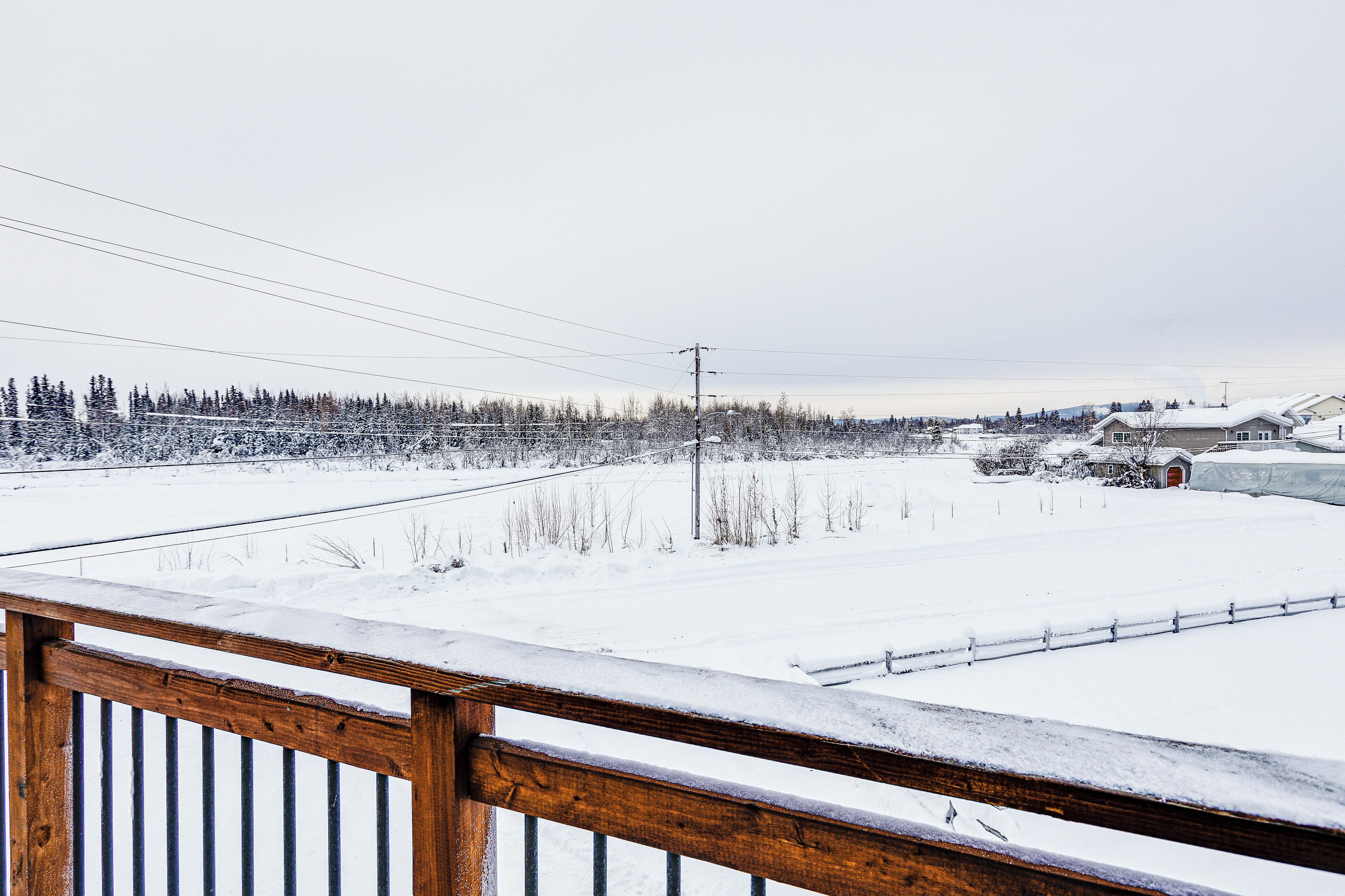 A snowy landscape with a wooden fence in the foreground.