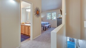 A hallway leading to a bedroom with a window, a sunburst decoration on the wall, and a ceiling fan.