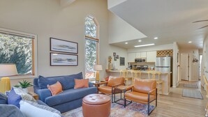 A spacious living room with a blue sofa, orange chairs, and a large window.