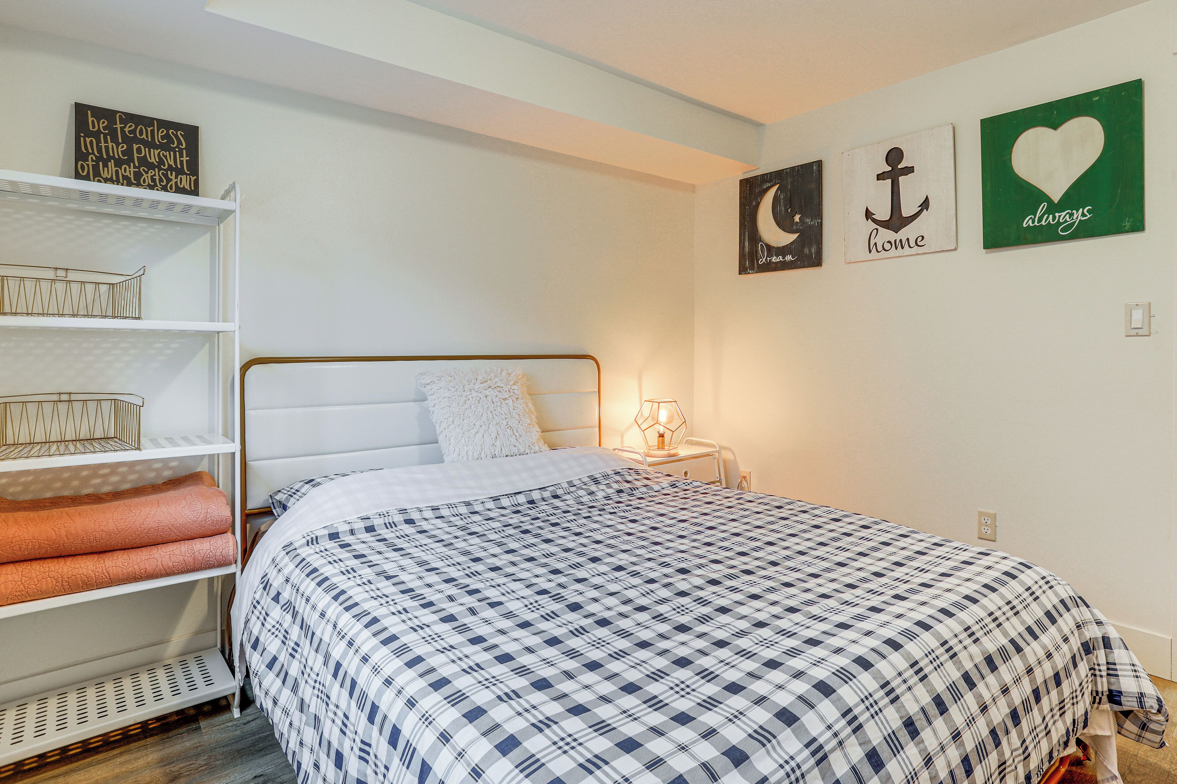 A neatly arranged bedroom with a bed, shelves, and motivational wall art.