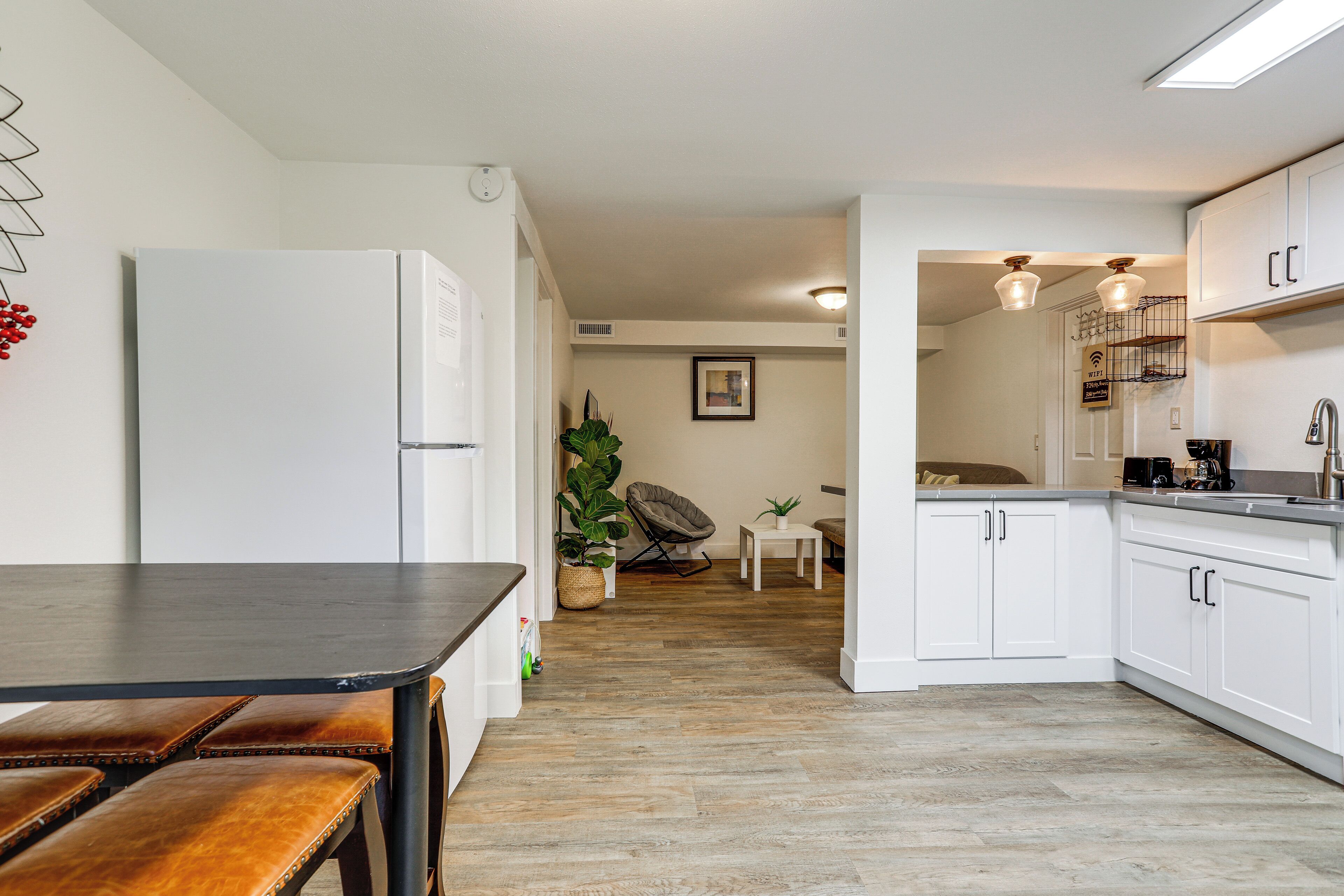 A modern kitchen with white cabinets, a black countertop, and a wooden dining table with benches.