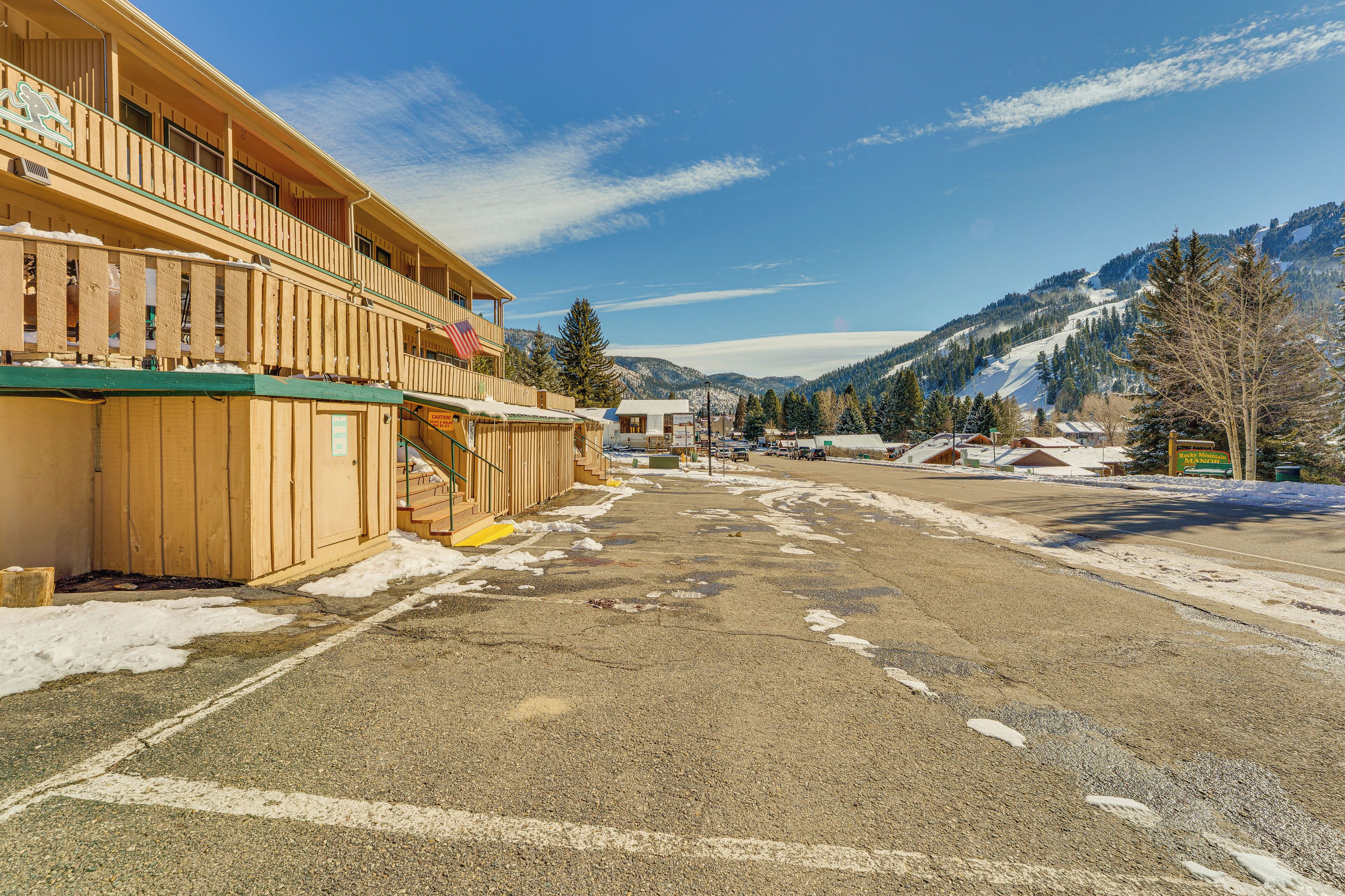 Un bâtiment à la façade en bois, doté d’un balcon et offrant une vue sur des montagnes enneigées.