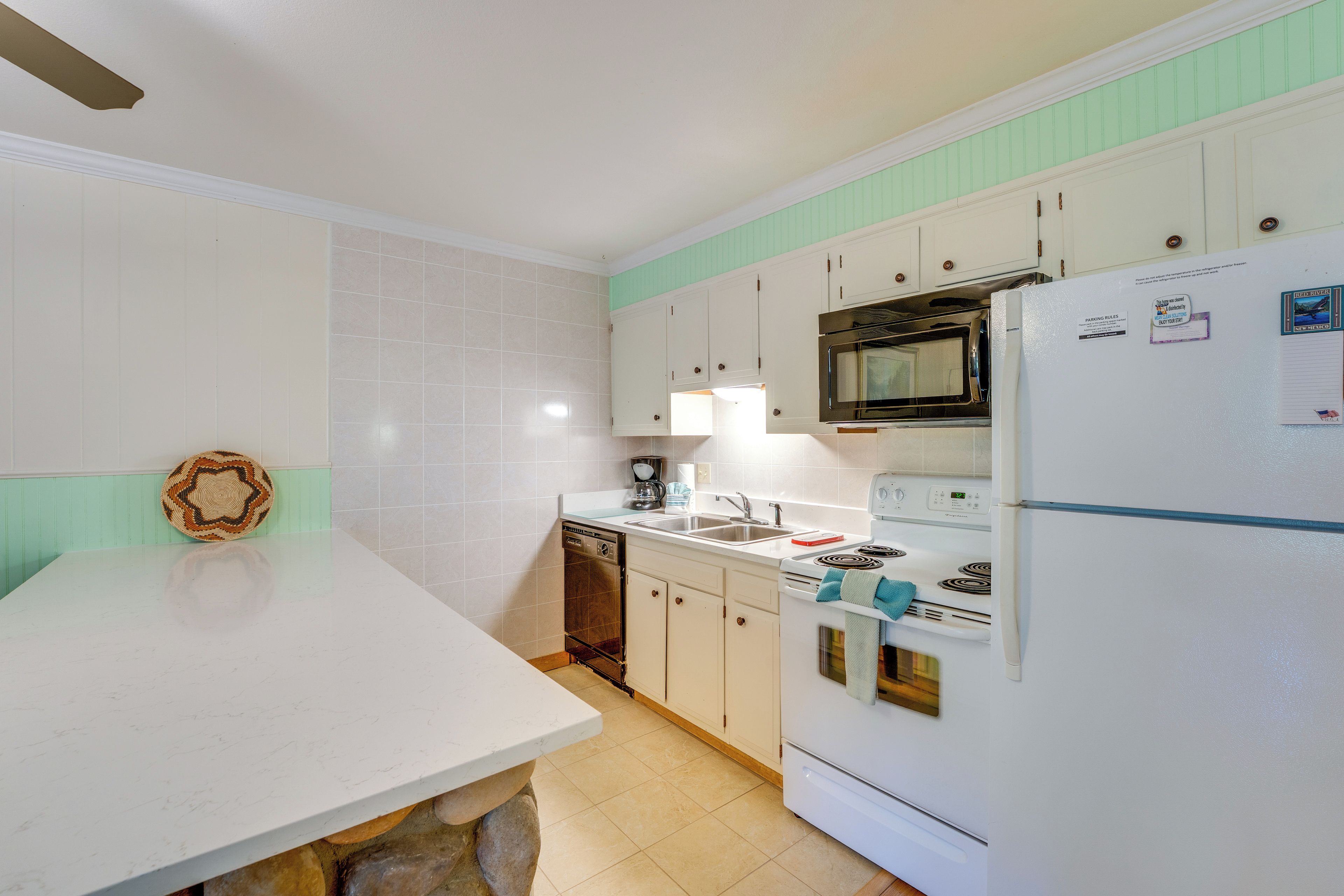 A kitchen with white cabinets, a built-in oven, a microwave, and a refrigerator.