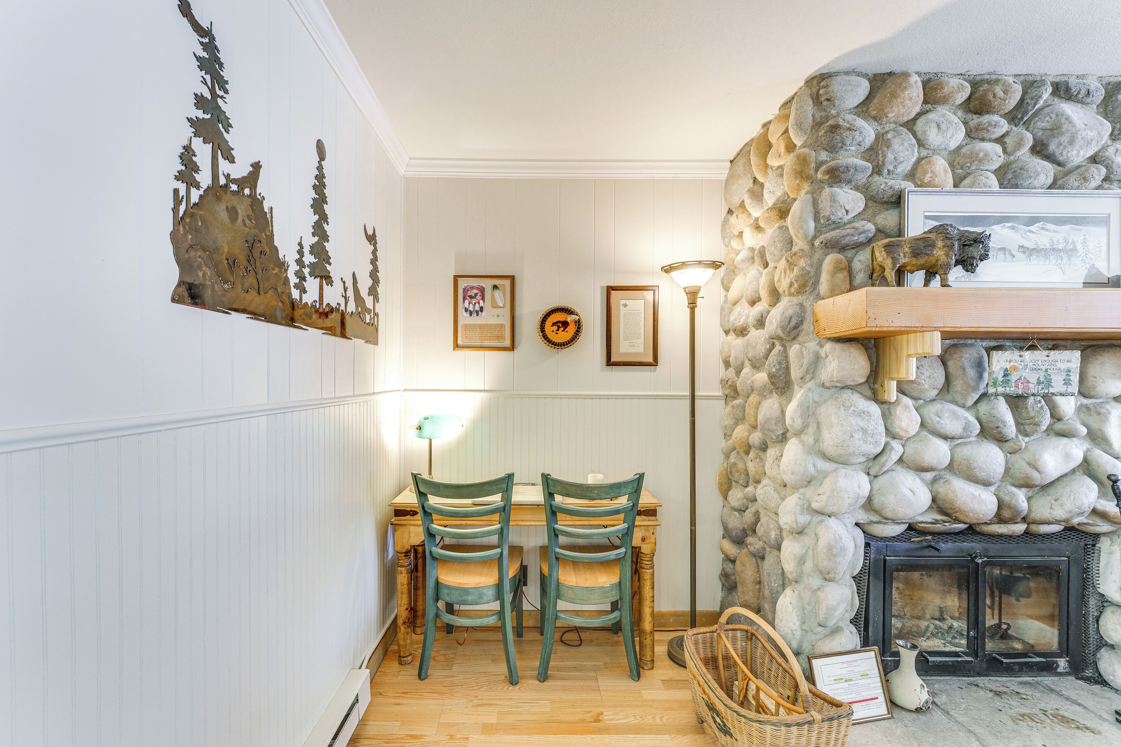 A dining area with a wooden table and chairs, a stone wall, and a fireplace.