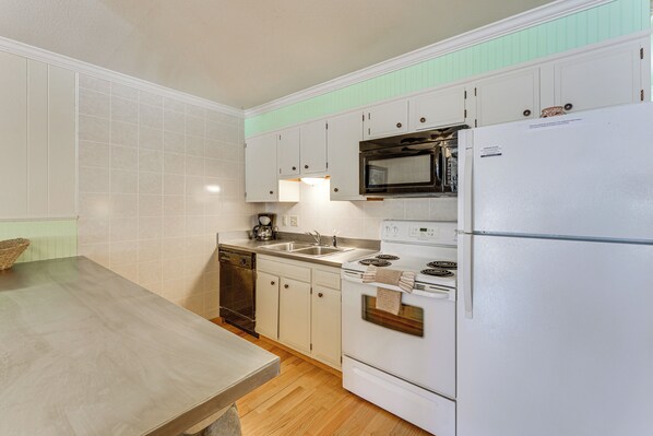 A modern kitchen with white cabinetry, a microwave, a refrigerator, a dishwasher, and a wooden countertop. - Main Street Red River Condo w/ Fireplace & Views! (Red River)